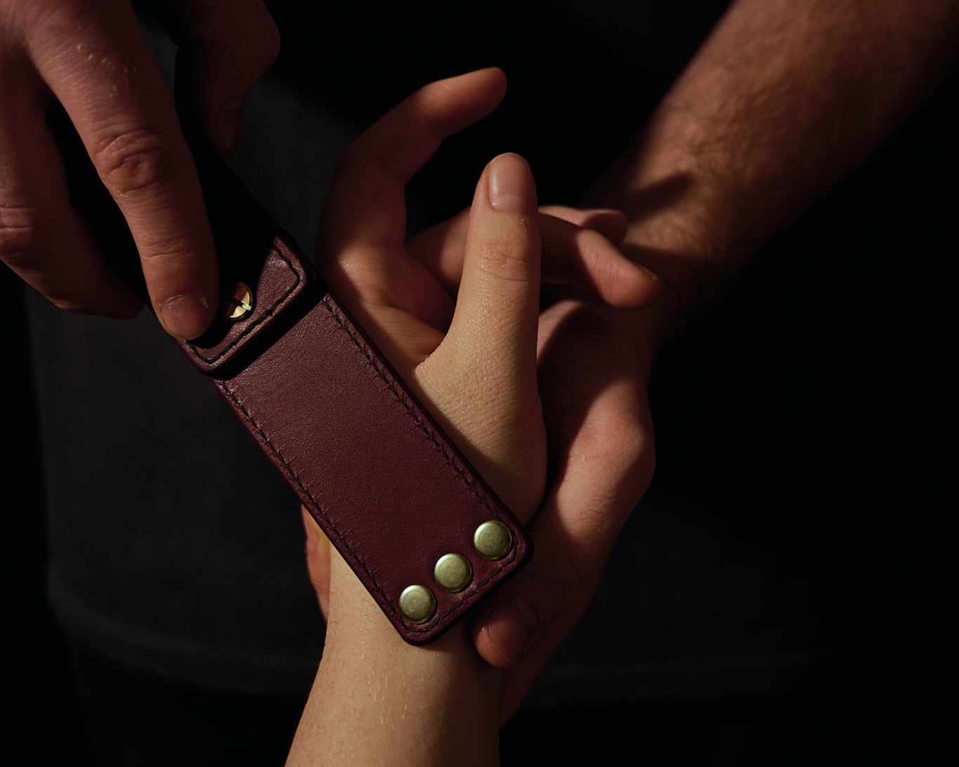 man holding woman's hand with leather strap on her hand