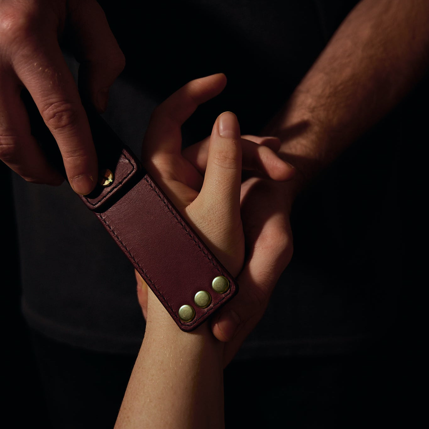 man holding woman's hand with leather strap on her hand
