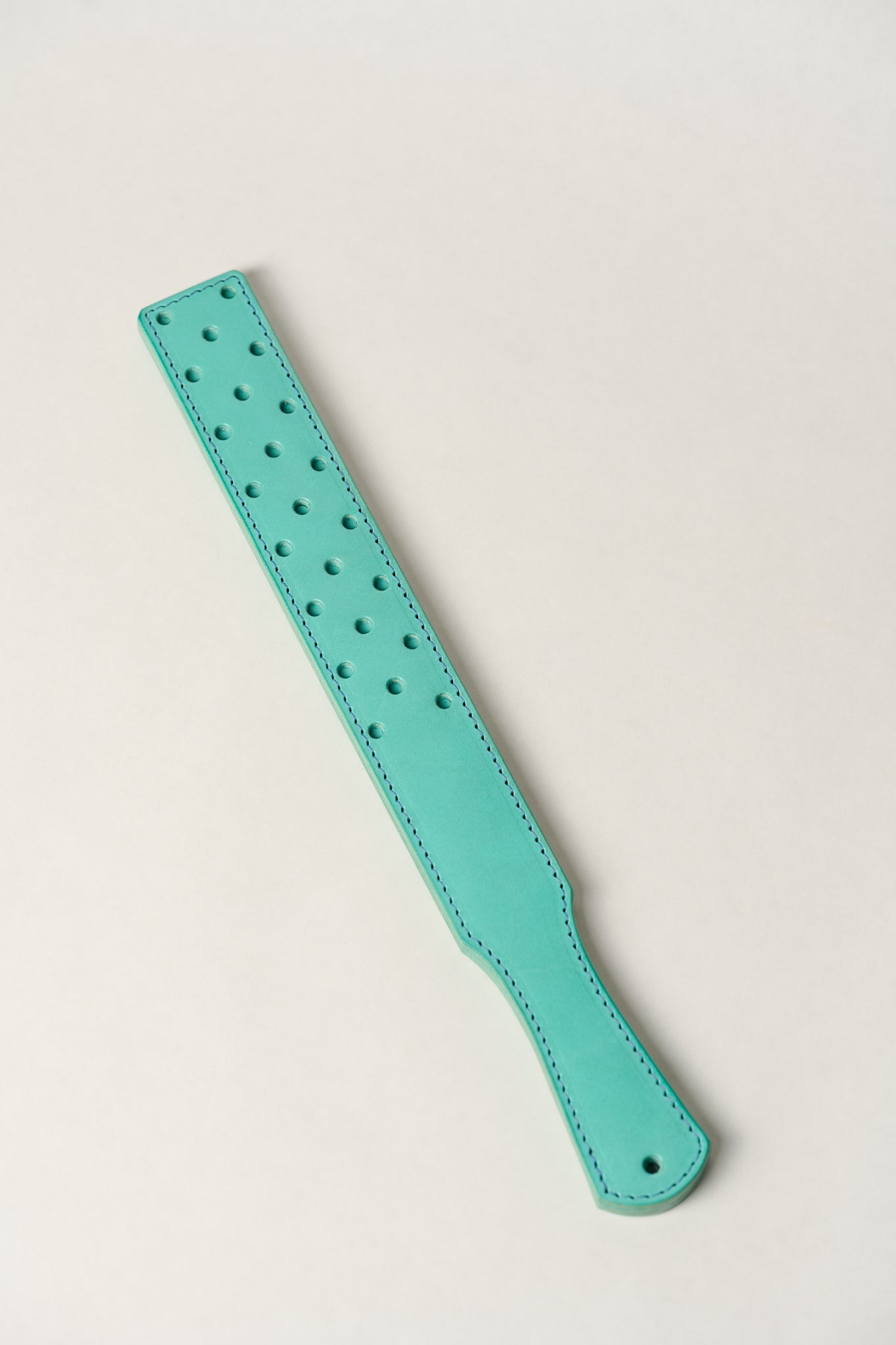 Turquoise leather strap with holes on a light gray background