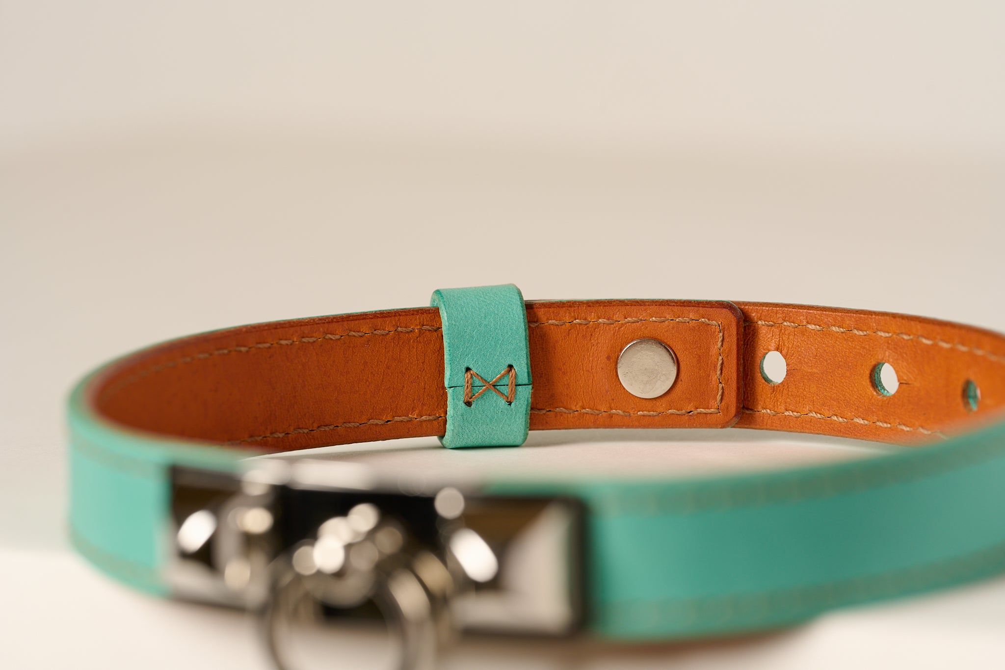 Teal and brown leather choker with metal clasp on a light background
