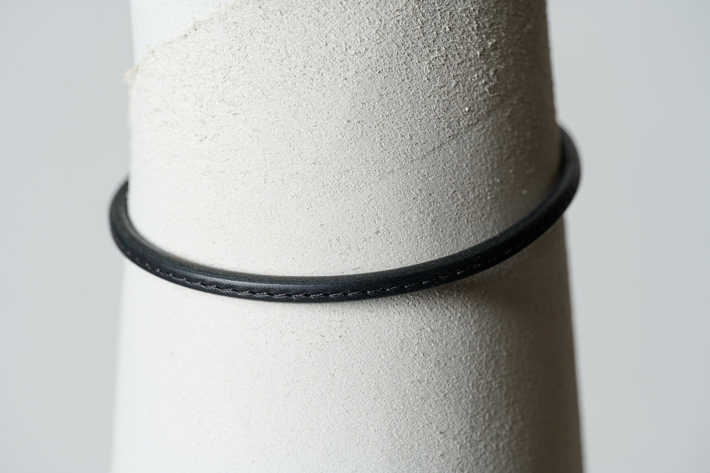 Black leather single continual ring with  black stitching through the center.