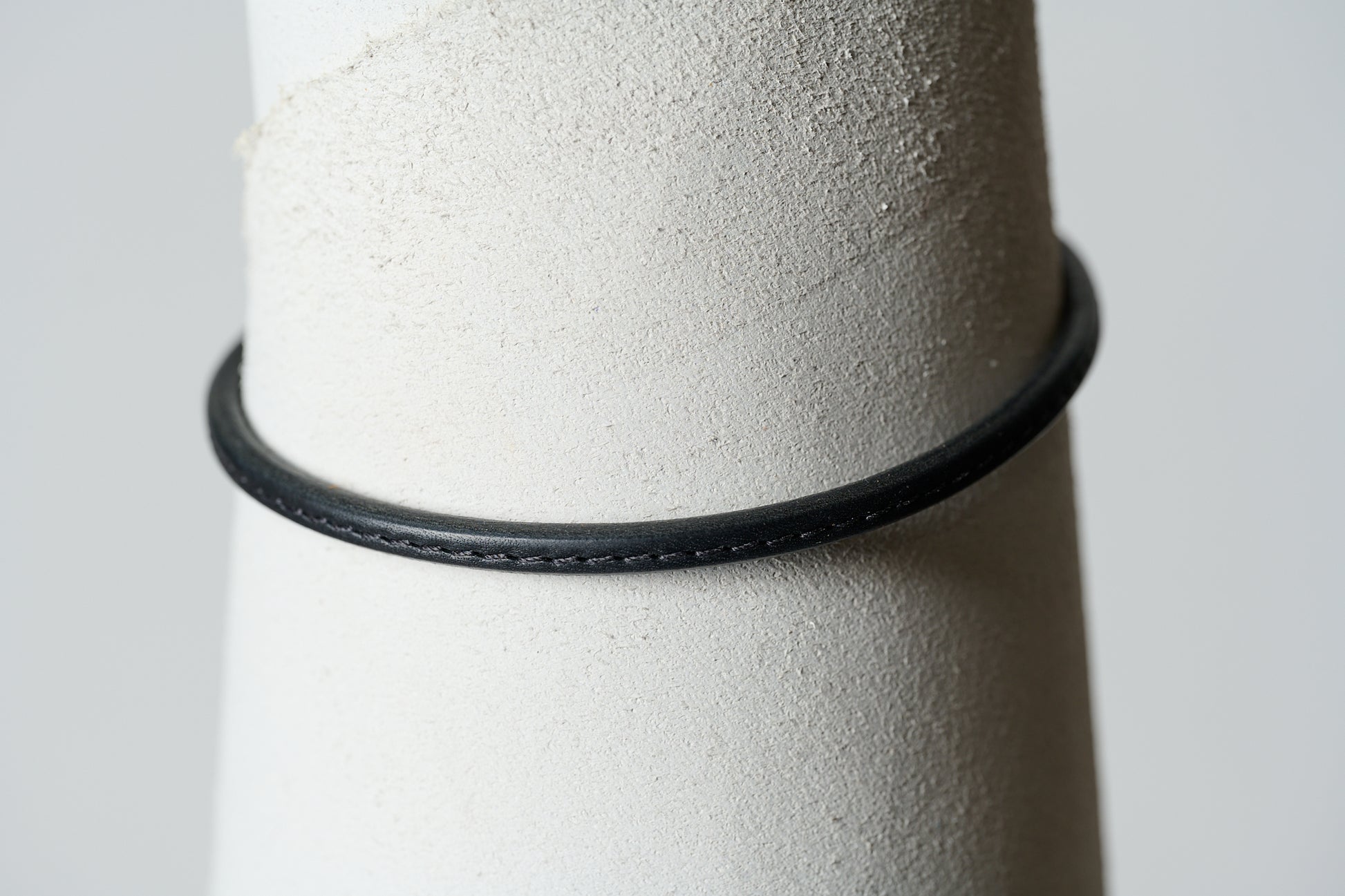 Black leather single continual ring with  black stitching through the center.