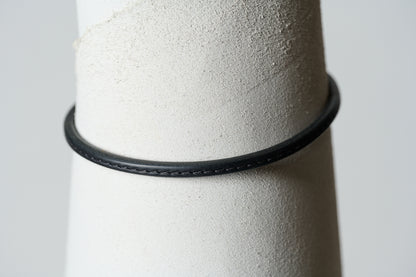 Black leather single continual ring with  black stitching through the center.
