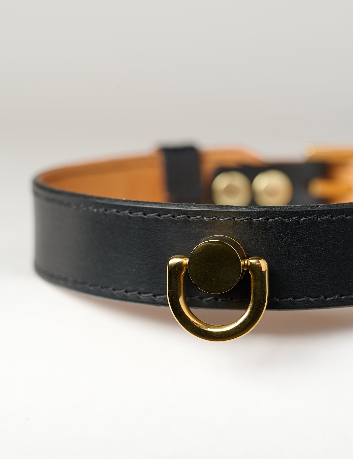 A close-up image of a luxury leather necklace with a gold stainless steel buckle, predominantly black in color.