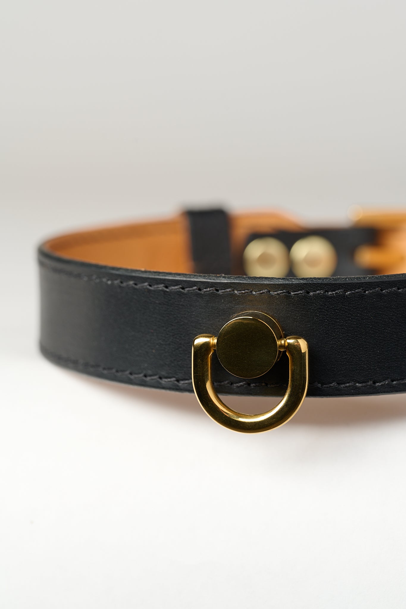 A close-up image of a luxury leather necklace with a gold stainless steel buckle, predominantly black in color.