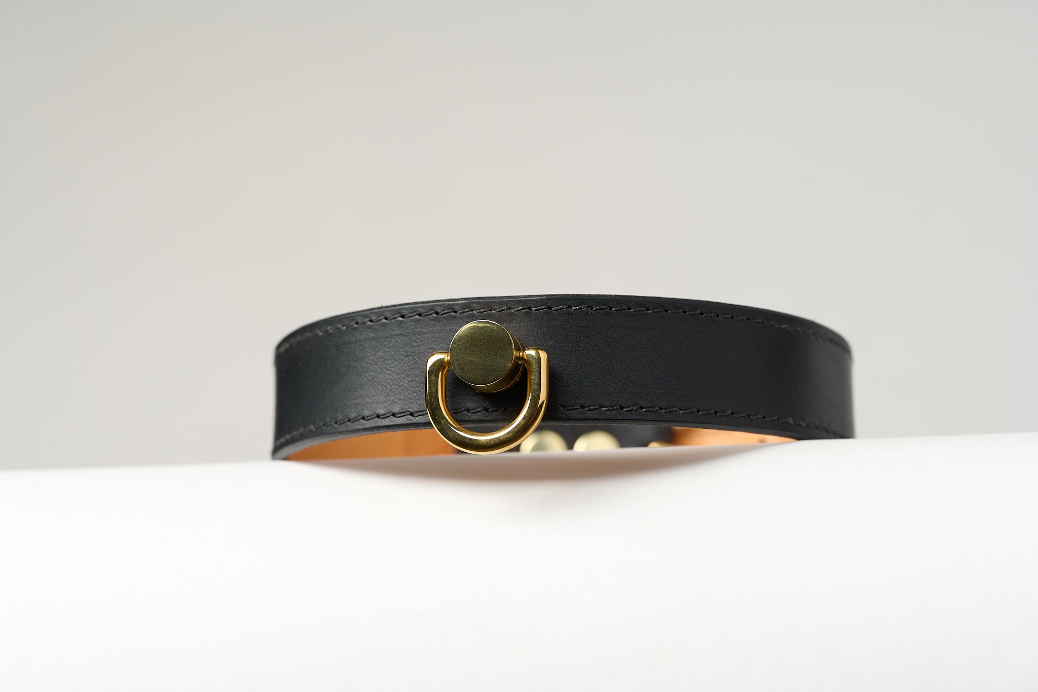 A close-up image of a luxury leather necklace with a gold stainless steel buckle, predominantly black in color.