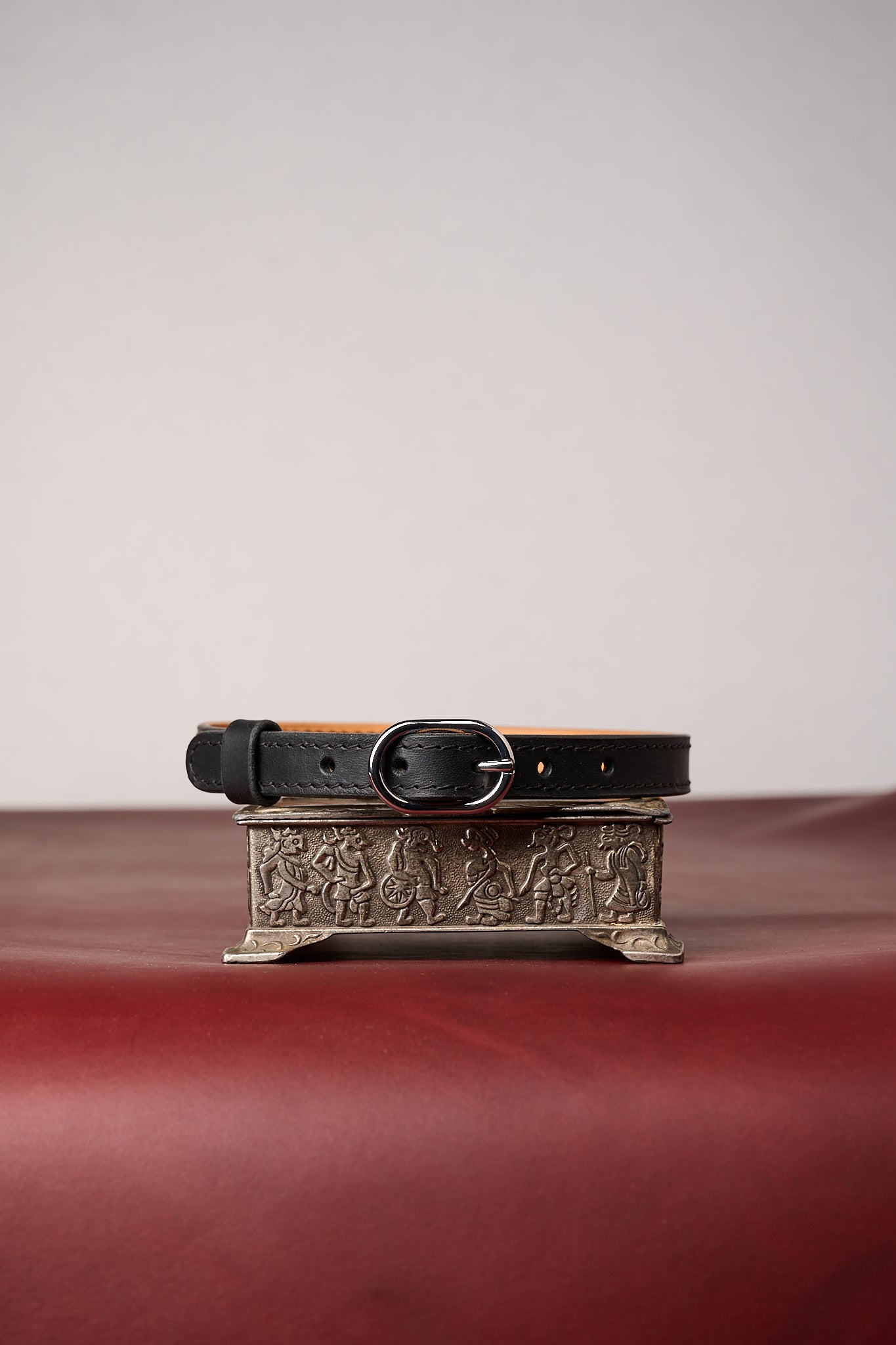 Black leather necklace with decorative buckle on a textured surface