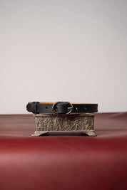 Black leather necklace with decorative buckle on a textured surface
