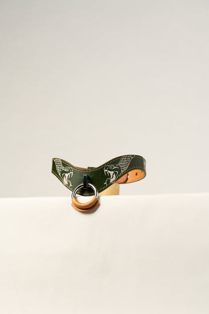 Green leather bdsm collar with a metal ring on a white background tattooed with snakes