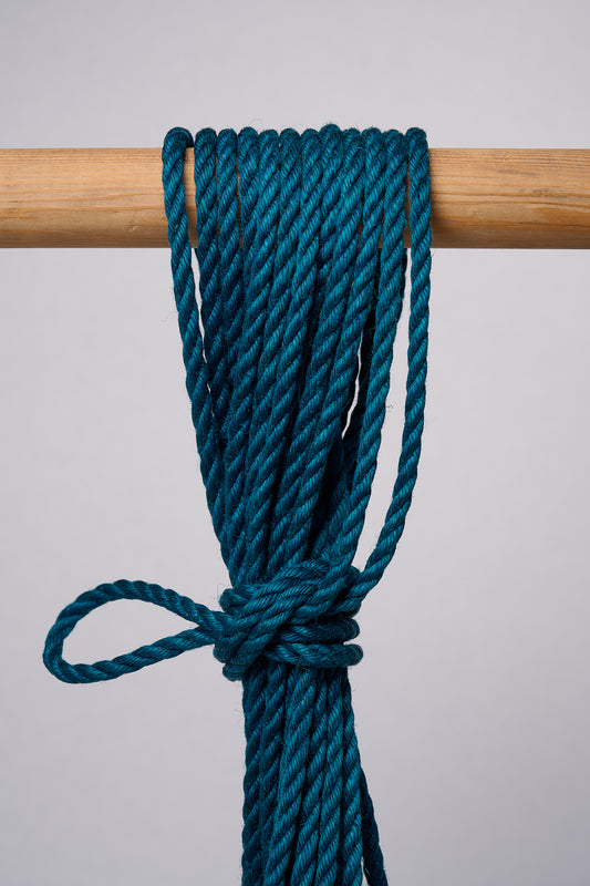 Blue Lovey Subby shibari Jute rope wrapped around and hanging from a wooden pole.