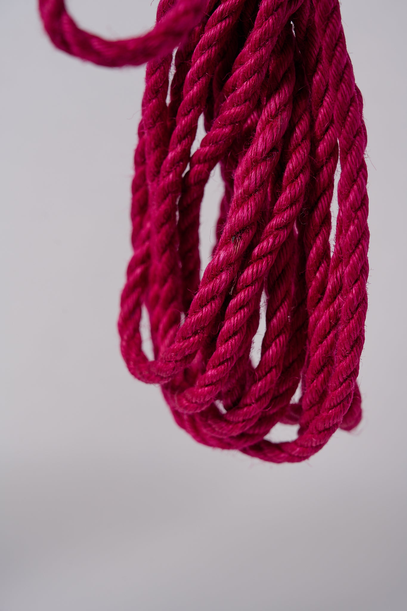 Pink Lovey Subby jute rope looped and hanging on a white background.