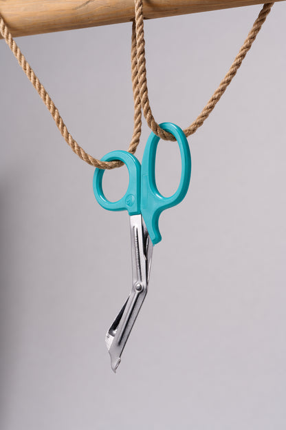 Silver emergency shears with light teal handles hanging from natural jute rope.