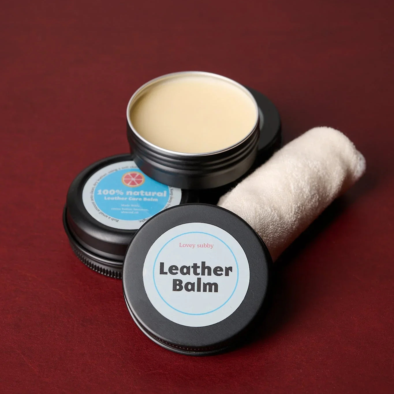 Handmade natural leather balm kit with cloth on a red surface