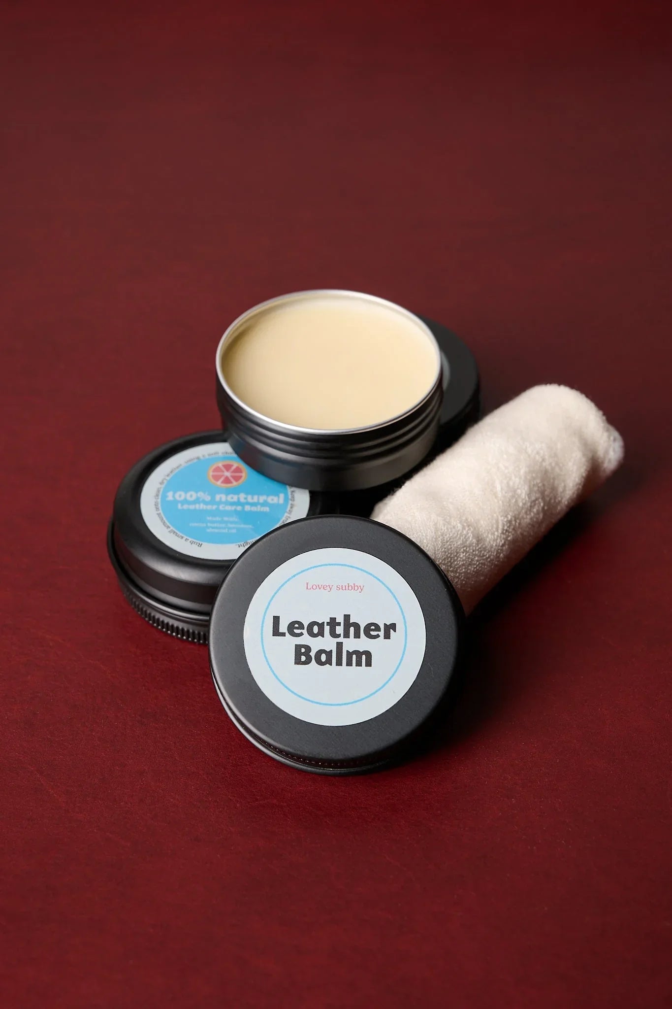 Handmade natural leather balm kit with cloth on a red surface