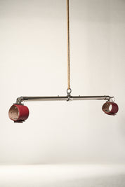 burgundy cuffs attached to silver metal bar hanging from rope