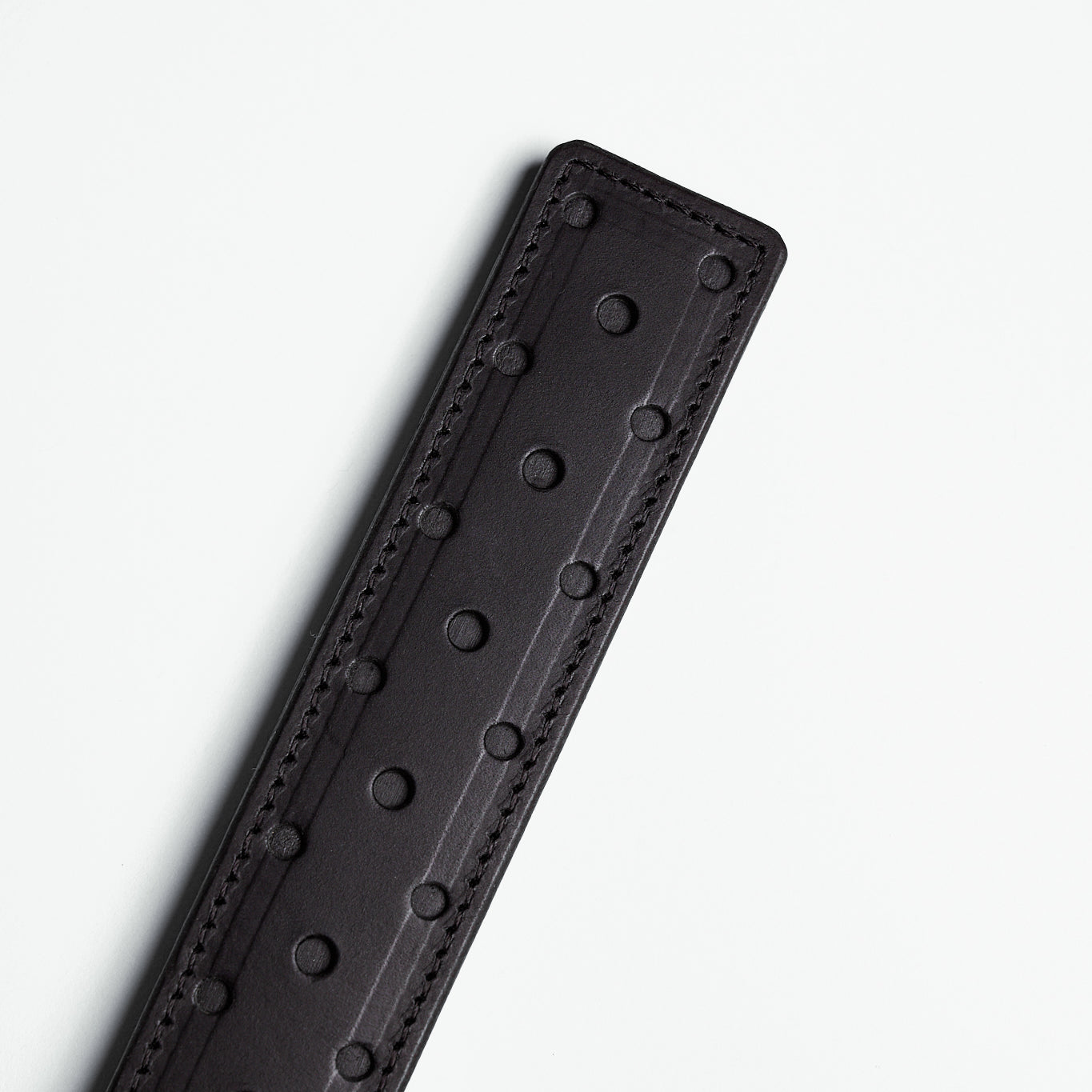 fenestrated black leather strap with black stitching on white background