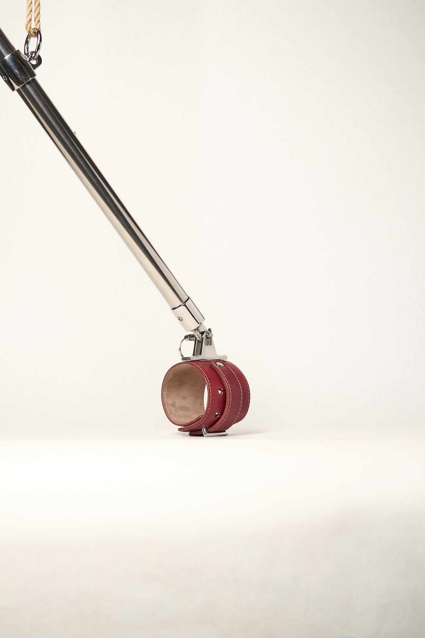burgundy cuffs attached to silver metal bar hanging from rope