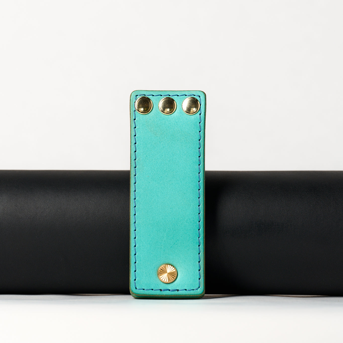 foldable blue leather travel size belt with rivets on white background.