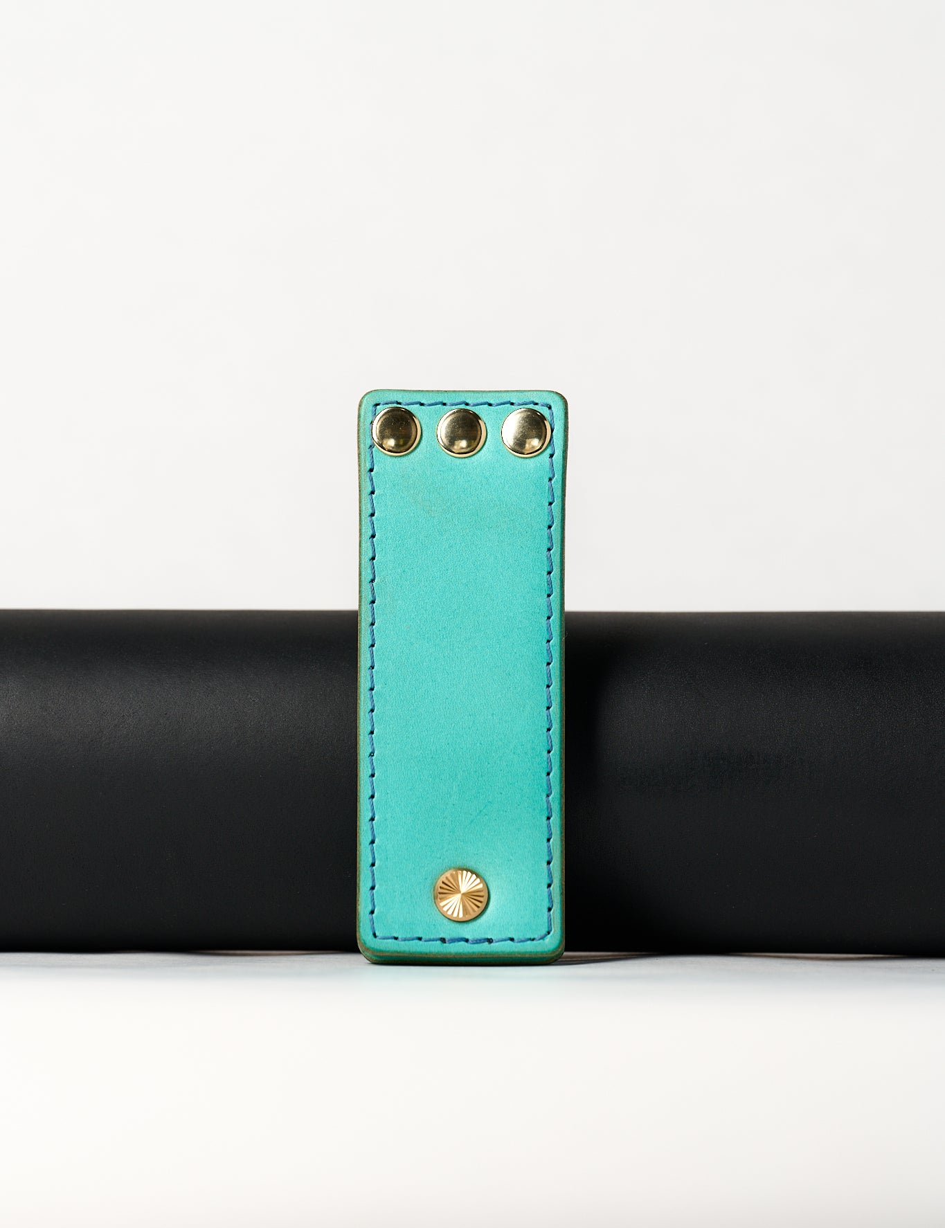 foldable blue leather travel size belt with rivets on white background.