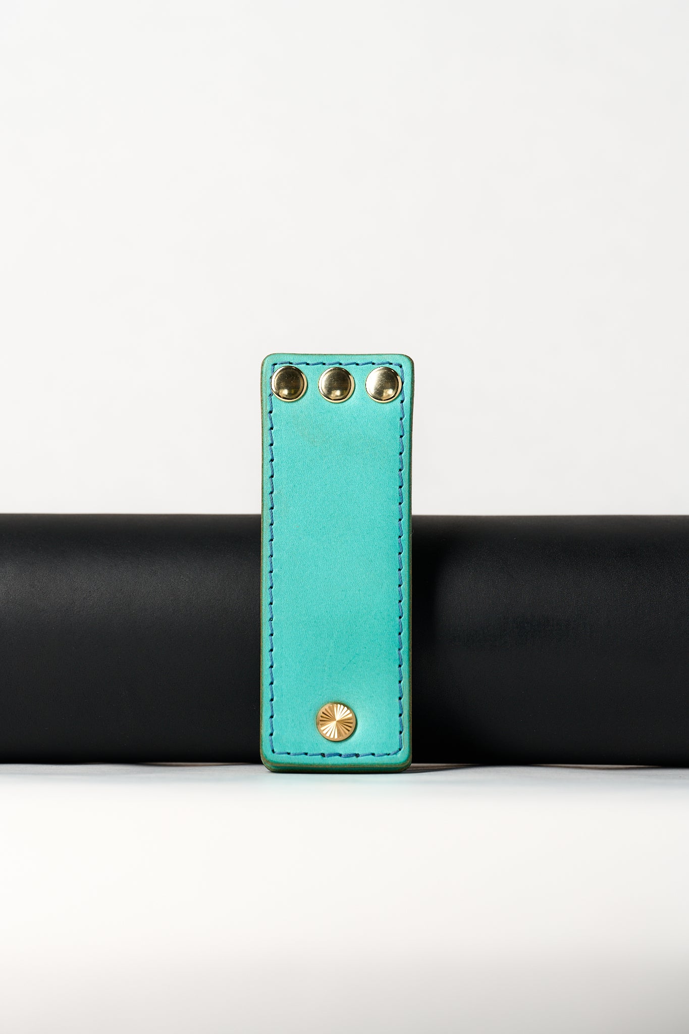 foldable blue leather travel size belt with rivets on white background.
