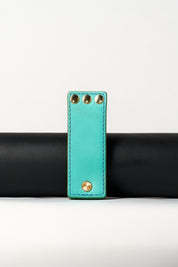 foldable blue leather travel size belt with rivets on white background.