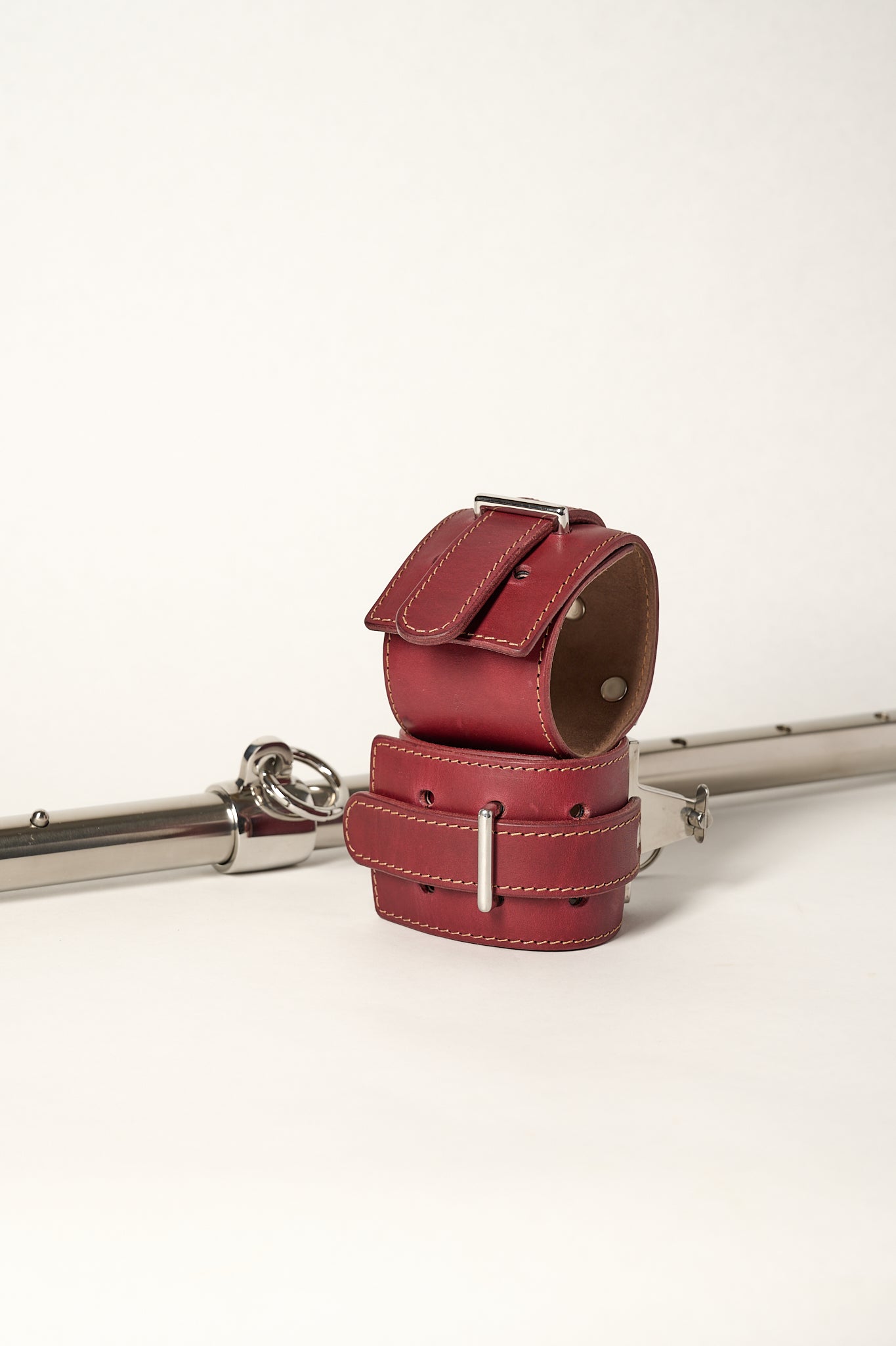 burgundy cuffs sitting in front of adjustable silver metal bar with o-ring