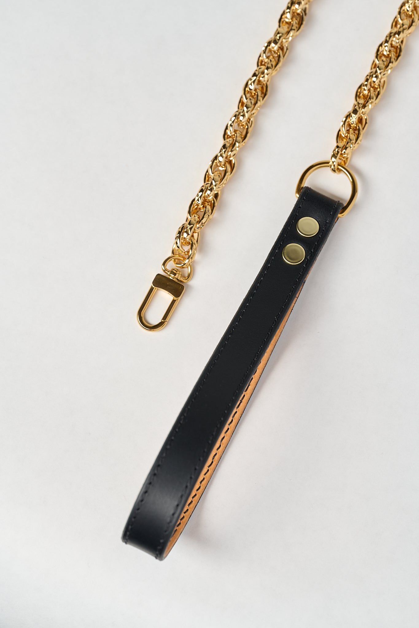 Black leather strap with gold chain on a white background