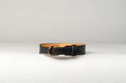 An image of a luxury leather necklace with a gold stainless steel buckle, predominantly black in color.