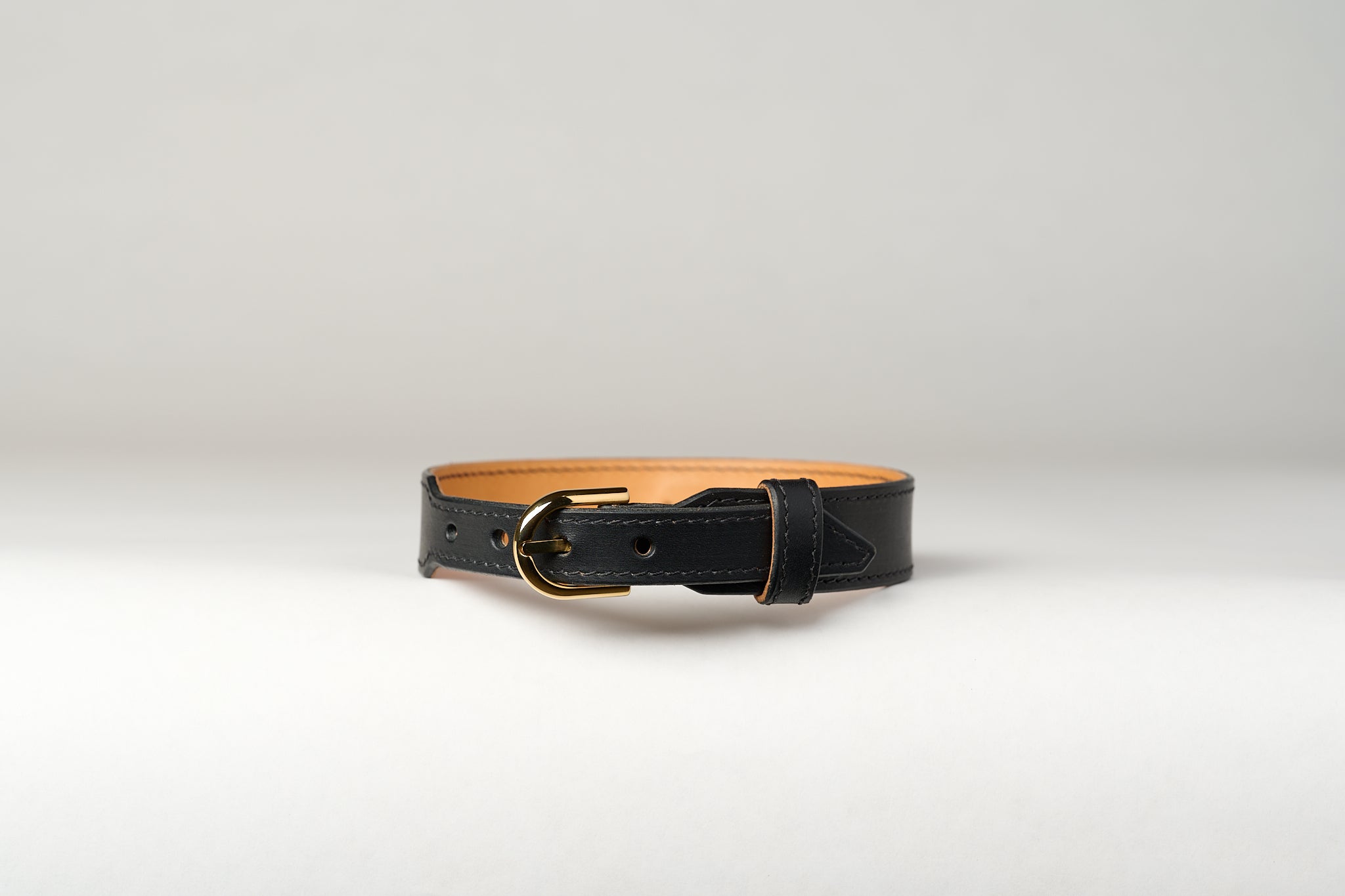 An image of a luxury leather necklace with a gold stainless steel buckle, predominantly black in color.