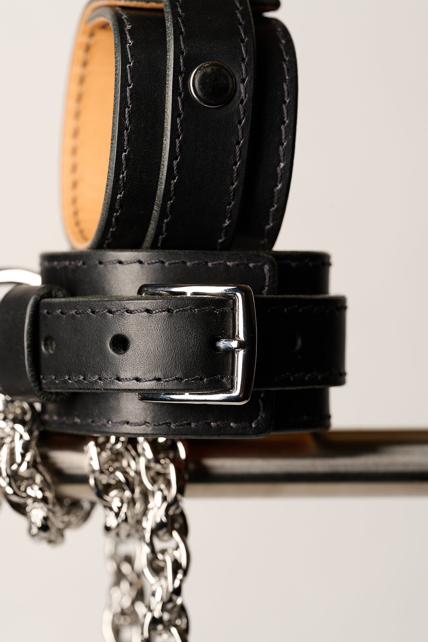 close-up of black leather wrist cuffs with silver chain