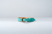 A close-up image of a luxury leather necklace with a gold stainless steel buckle, predominantly blue in color.