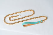 Gold chain with a turquoise leather strap on a light gray background