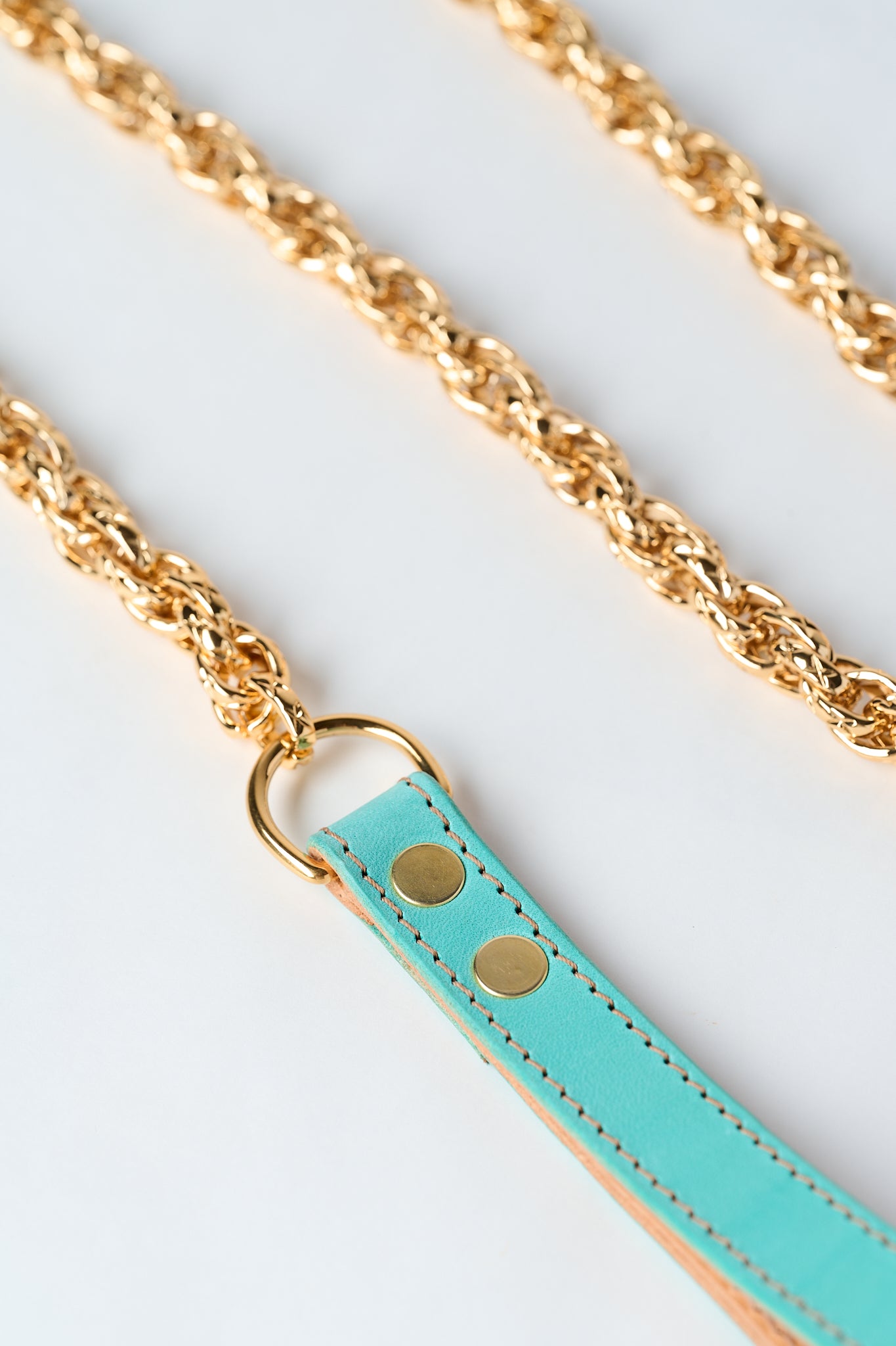 blue leather strap with gold stainless steel chain and pendant on white background
