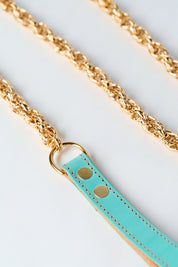 blue leather strap with gold stainless steel chain and pendant on white background