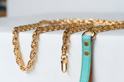 Gold chain and turquoise strap on a white surface