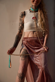 Tattooed model wearing blue luxury leash collar, gold chain, and pink velvet skirt.