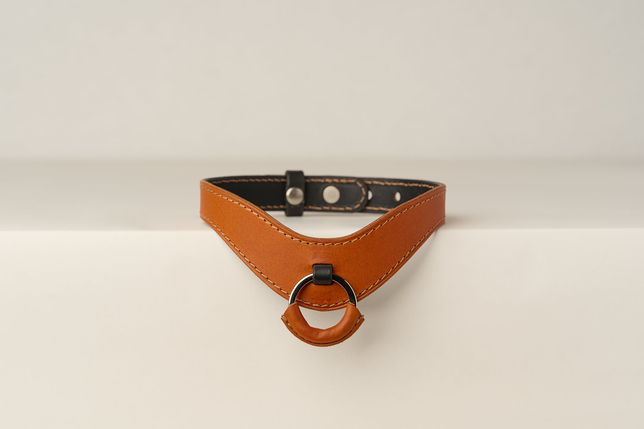 Brown leather necklace with a ring on a beige background