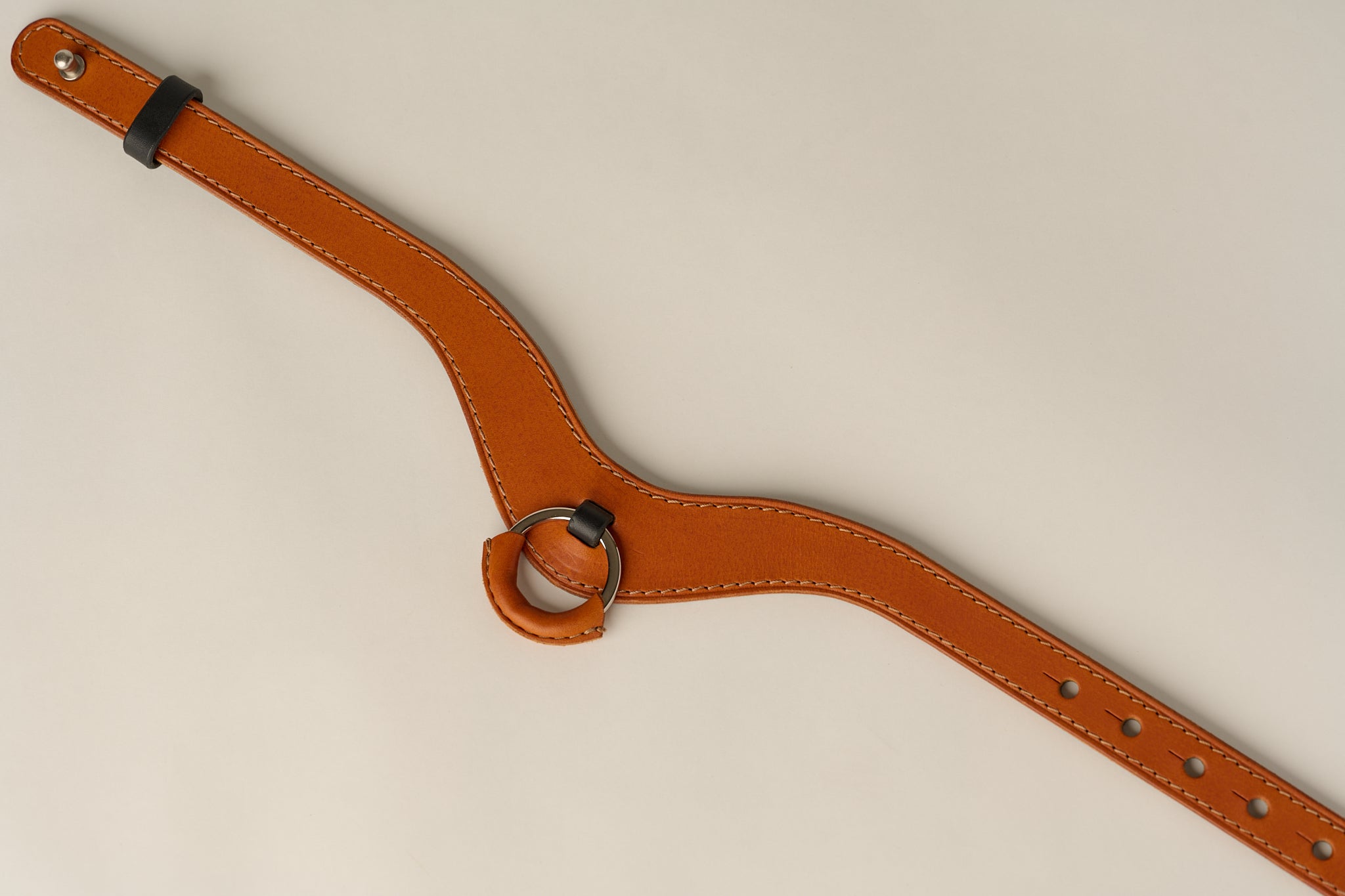 Brown leather necklace with a ring on a beige background