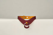 burgundy and yellow leather necklace with a ring on a beige background