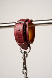 Red leather wrist cuff with silver metal clasp on a white background