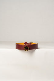 A close-up image of a luxury leather necklace with pendant and a gold stainless steel buckle, predominantly burgundy in color.