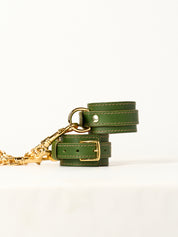 Green leather wirst cuffs  with gold hardware on a white background