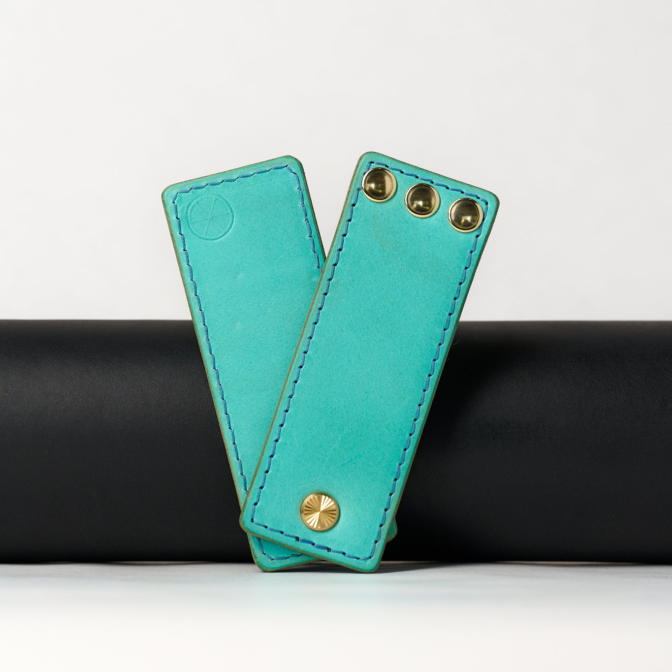 foldable blue leather travel size belt with rivets on white background.