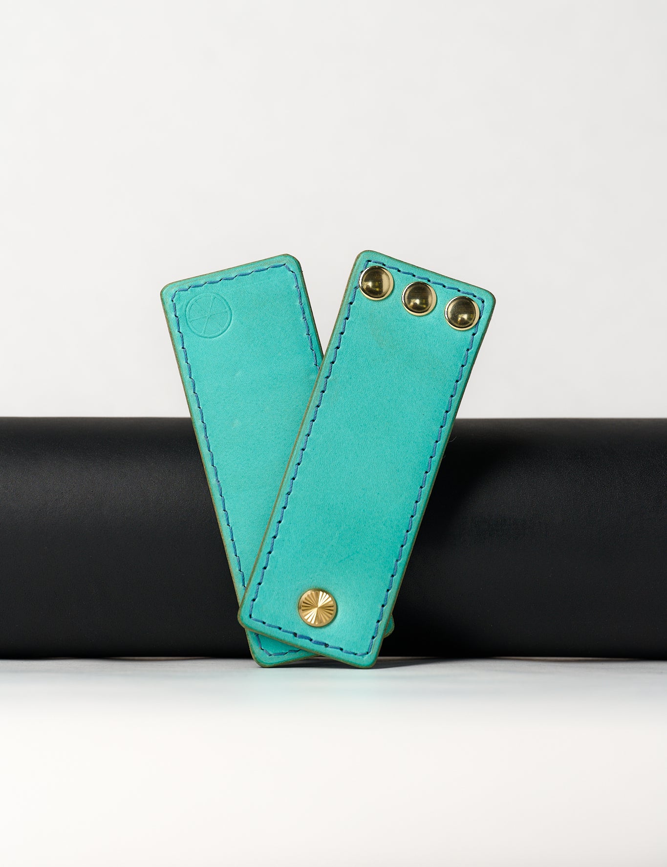 foldable blue leather travel size belt with rivets on white background.