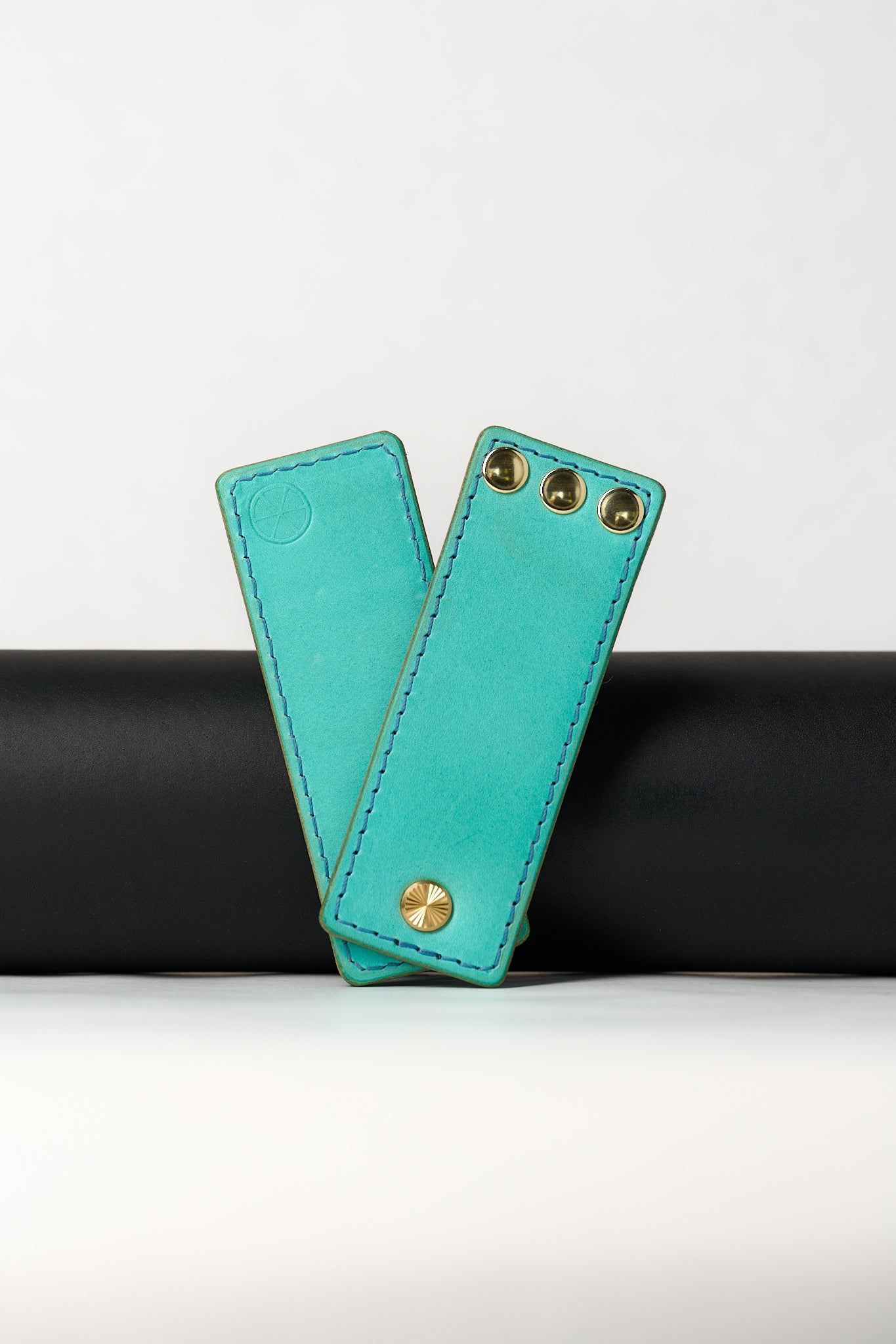 foldable blue leather travel size belt with rivets on white background.