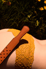 fenestrated leather strap orange brown laying in field of dandelions on a woman in flower bottoms