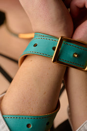 woman's hands restrained with blue leather belt on black background