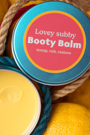 Booty balm container with a colorful label on a textured background