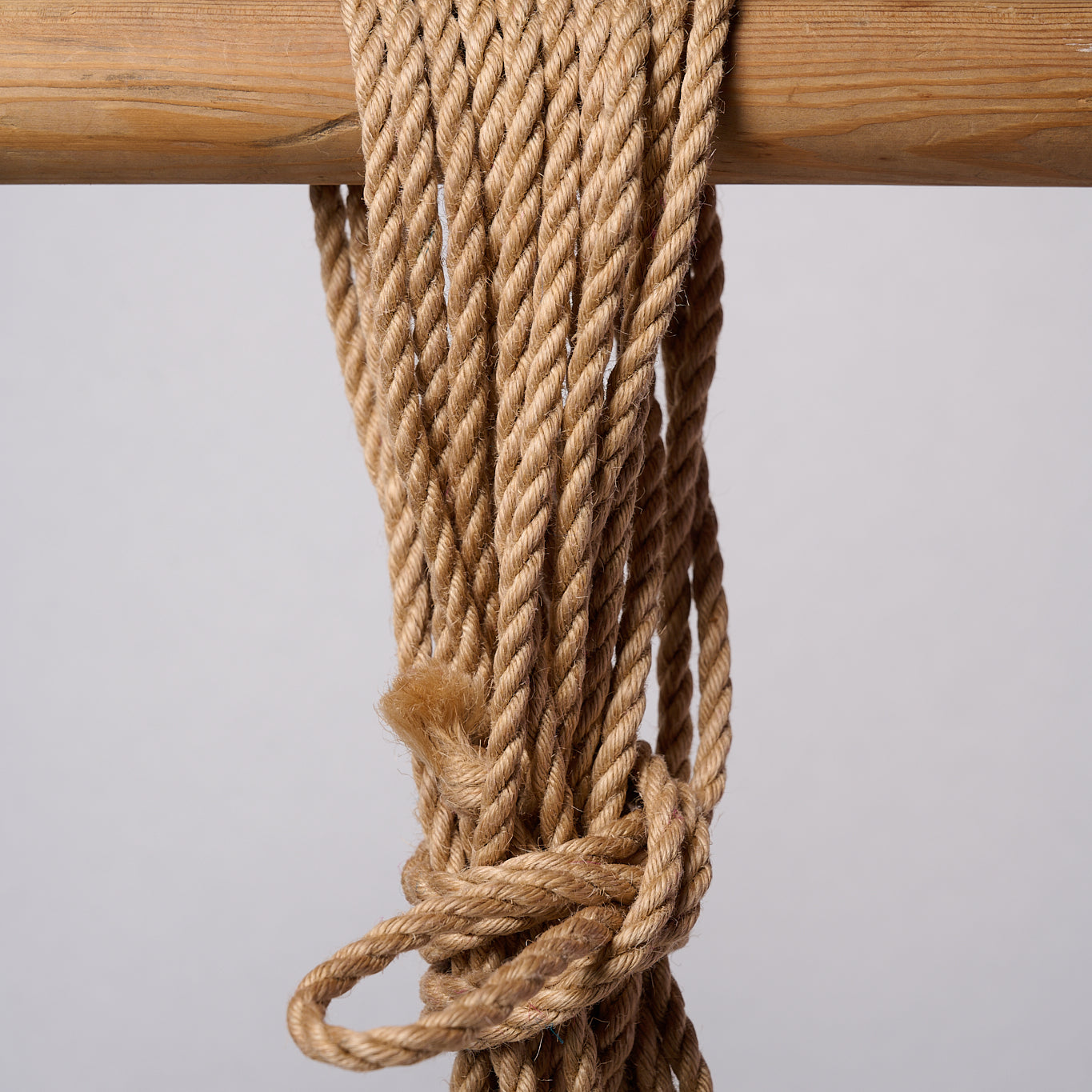 Natural Lovey Subby jute rope looped and hanging on a white background.