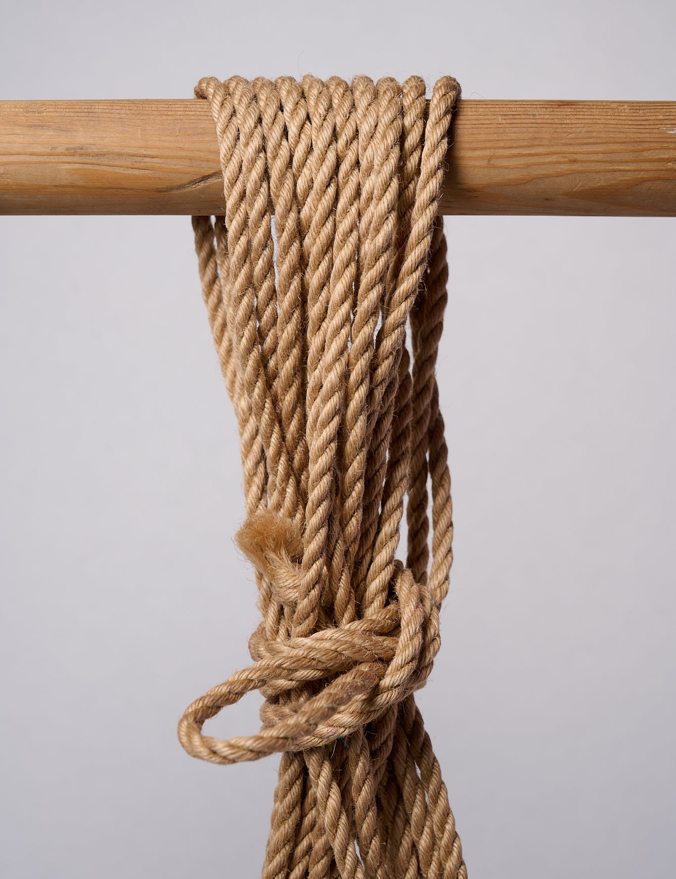 Natural Lovey Subby jute rope looped and hanging on a white background.
